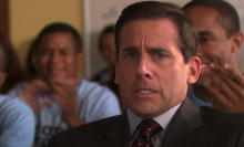 A man (Steve Carell as Michael Scott on "The Office") sitting at a desk in a classroom surrounded by high school students.