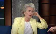 Emma Thompson in a lemon yellow suit with a pensive look on her face. 