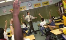 kids in a classroom raising their hands