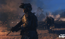solider wearing nightvision googles looks out to the distance as the field around him is in flames
