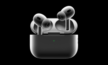 a pair of second-generation airpods pro with their charging case against a black background