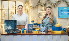 Two women standing in front of a table full of holiday deals from Walmart