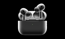 A pair of second-generation AirPods Pro with their charging case against a black background.