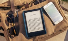 An e-reader called the Amazon Kindle is placed on a surface with some text on its display