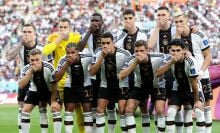 Germany players pose with their hands covering their mouths as they line up for the team photos.