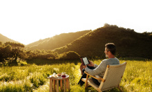 man reading Amazon Kindle outdoors