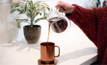 Woman pouring coffee into a copper Ember mug