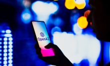 A person on their phone that has the OpenAI logo on it. 