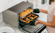 Woman taking fries and chicken wings out of an air fry oven 