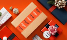Amazon box and wrapped gifts sitting on orange surface