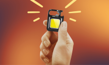 hand holding maxlight mini flashlight with orange background