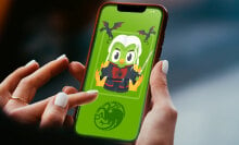 A phone screen with an image of the green Duolingo owl with silver Targaryen hair, red and black armor, and two dragons flying in the background.