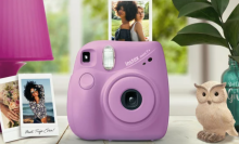 Fujifilm Instax in pink with a photo coming out, an owl decoration to the right and two pictures to the left