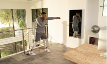 A man is shadow boxing in front of an exercise mirror.