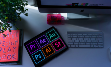 tablet with adobe program logos next to keyboard on desk