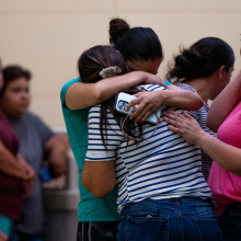 Two women hugging with a crowd around them following a mass shooting in Uvalde, Texas. 