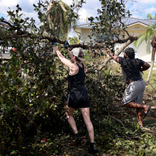 Allison Huston (L) and Malik Jean clear a tree from a road after Hurricane Ian passed through on October 1, 2022 in Fort Myers, Florida. The Category 4 hurricane caused severe damage to the region.
