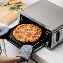 Person taking pizza out of Ninja Foodi toaster oven and air fryer