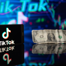 a smartphone showing the TikTok logo, and a dollar.