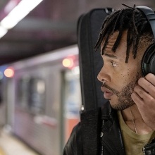 man in subway wearing black bose headphones and looking to the side