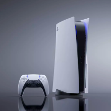 the playstation 5 next to its dualsense wireless controller against a reflective gray background