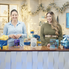 Cathy Pedrayes and Gaby from Mashable standing in a room decked with holiday decor, three products in front of them.