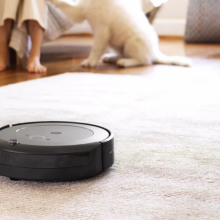 roomba robot vacuum on carpet with dog in background