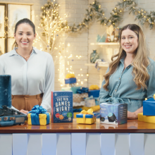 Two women standing in front of a table full of holiday deals from Walmart