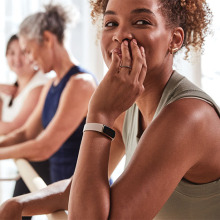 A woman wearing a fitness tracker is smiling at someone