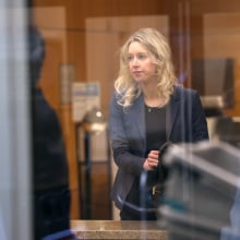 A blonde woman is seen through a see-through glass panel in a court building.