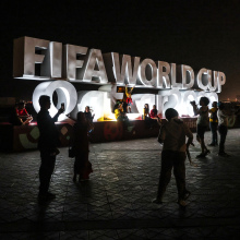 Fans pose around a sign for the Qatar World Cup