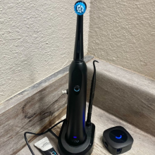 electric toothbrush on charging stand in the corner of a bathroom counter