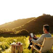 man reading Amazon Kindle outdoors