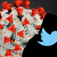 The Twitter logo seen displayed on a smartphone. The computer model of the COVID-19 coronavirus is displayed as the background.