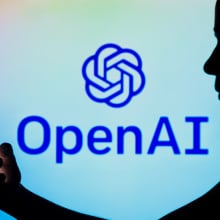 a mobile phone user in front of the OpenAI logo