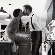 A couple kiss in their kitchen.
