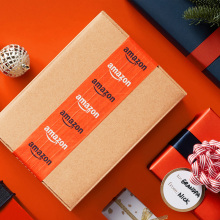 Amazon box and wrapped gifts sitting on orange surface