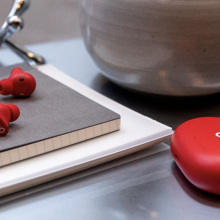 Red Beats Studio Buds on a desk on top of notebooks