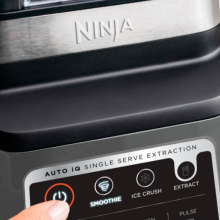 Finger using a feature in the Ninja Professional Plus Blender against a white kitchen counter