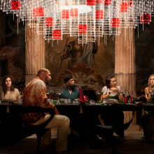 A group of friends have dinner in a luxurious setting. 