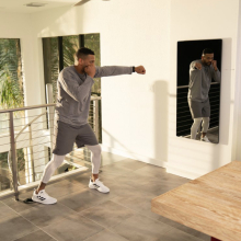 A man is shadow boxing in front of an exercise mirror.