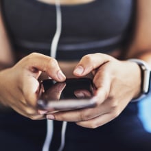 Closeup shot of a sporty woman using a cellphone while exercising in a studio.