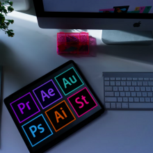 tablet with adobe program logos next to keyboard on desk