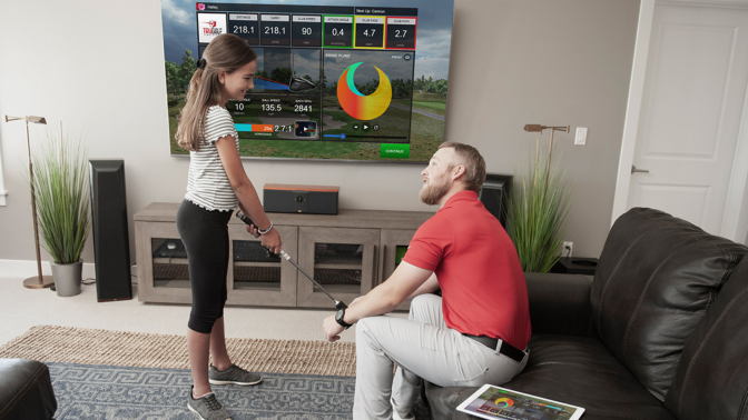 dad and daughter playing with the trugolf simulator