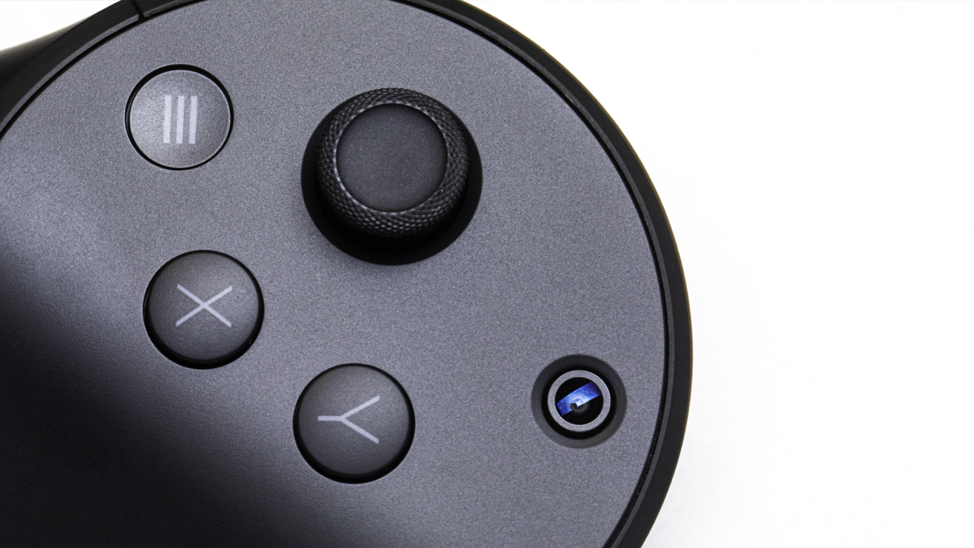 A close up of the face of the controller which is round and houses two round X and Y buttons, a joystick, a menu button and the tiny lens of a camera.