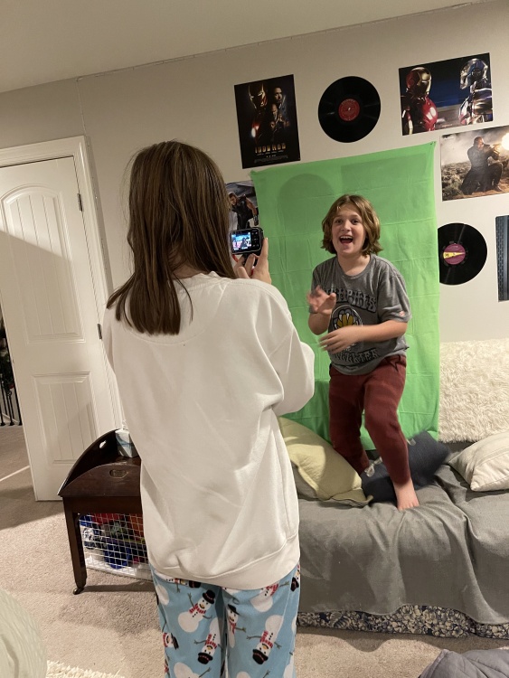 kids recording each other with mini vlogging camera against a green screen