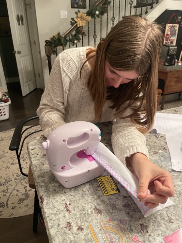 girl sewing fabric on toy sewing machine