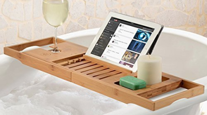 Wooden tray suspended above bath carrying glass of wine, tablet, candle, and bar soap