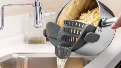 a close-up of a pot of pasta being drained with a clip-on strainer