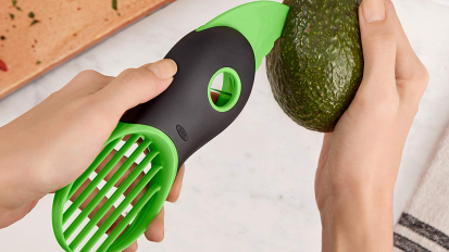 a close-up of a person slicing an avocado with the oxo good grips 3-in-1 advocado slicer
